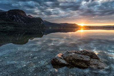 Rocks in sea against sky during sunset