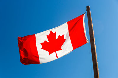 Low angle view of flag against blue sky