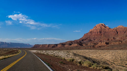 Road by mountains against blue sky