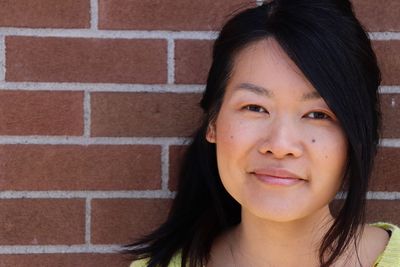 Close-up portrait of smiling woman against wall