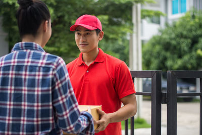 Man delivering package to female customer at gate