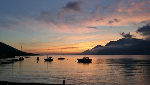 Silhouette boats in sea against sky during sunset