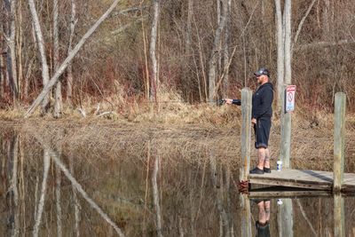 Man standing on field by lake in forest