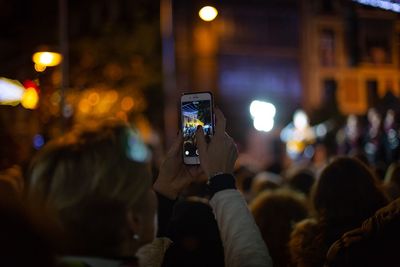 People photographing illuminated smart phone at night