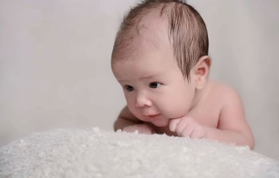 Shirtless baby boy on textile against white background