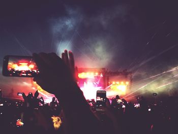 Crowd at music concert against sky at night