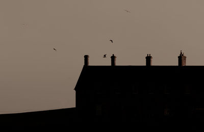 Low angle view of silhouette building against sky during sunset