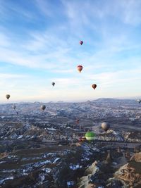 Hot air balloon flying over city against blue sky