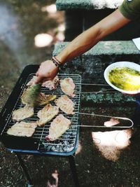High angle view of woman preparing food on barbecue grill