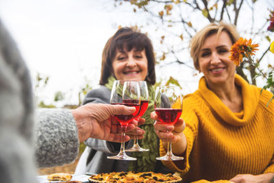 Friends toasting drinks while sitting outdoors during autumn