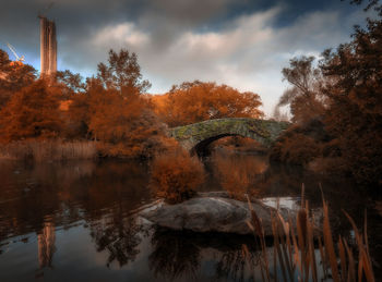 Reflection of trees on bridge against sky during autumn