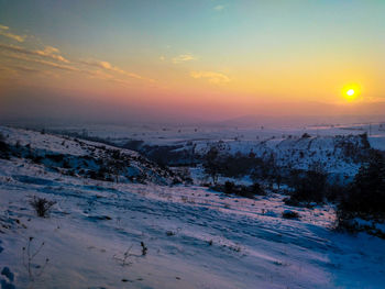 Scenic view of frozen landscape against sky during sunset