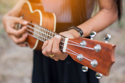 Midsection of woman playing guitar