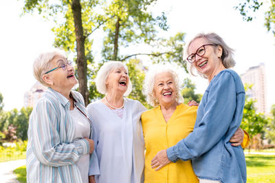 Portrait of smiling friends standing against trees