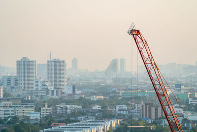 Orange construction crane and dusty city