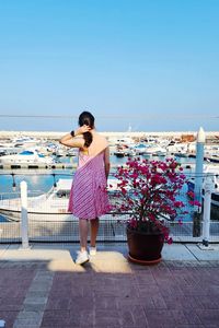 Rear view of woman standing at beach against clear blue sky