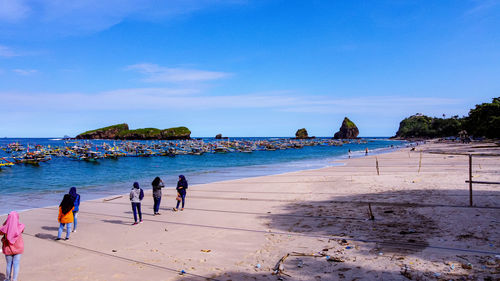 People on beach against blue sky