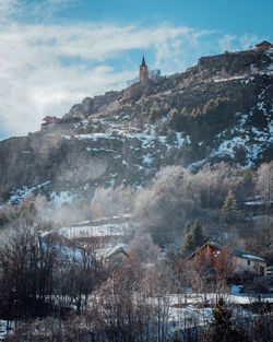 View of buildings on mountain against cloudy sky