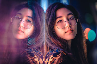 Portrait of young woman by window with reflection