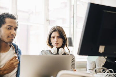 Computer programmers looking at laptop while programming in office