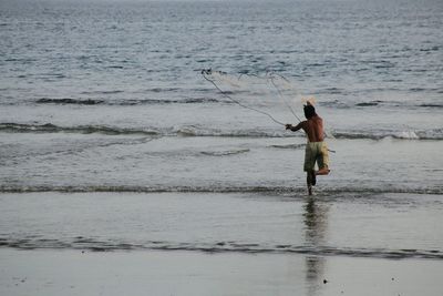 Full length of man fishing on sea shore