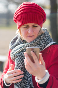 Young woman wearing warm clothing holding mobile phone