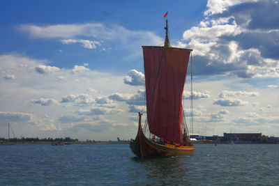 Ship in sea against cloudy sky