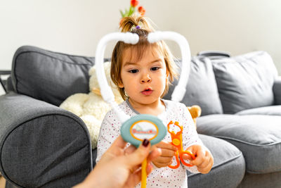 Close-up of baby girl sitting on sofa at home