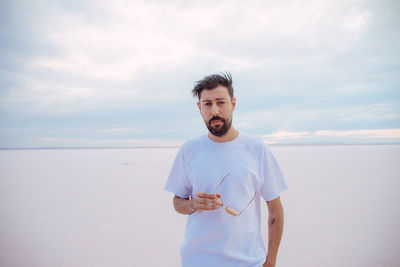 Young man standing in sea against sky