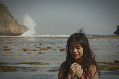Portrait of woman standing at beach against sky