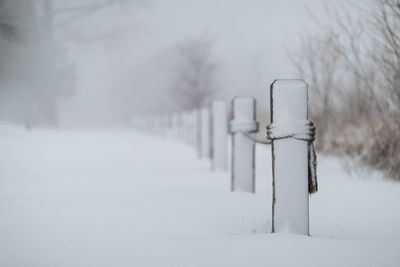 Snow covered wooden post on field during winter