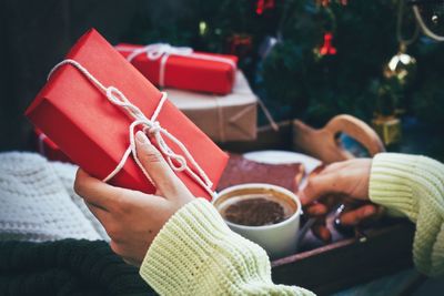 Cropped image of hands holding gift and coffee cup