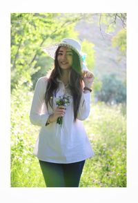 Portrait of smiling young woman standing against plants