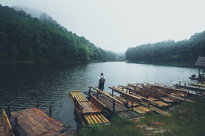 Rear view of man looking at lake against clear sky