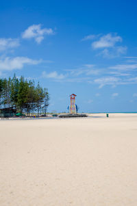 Lighthouse on beach against sky