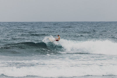 Man surfing in sea against clear sky