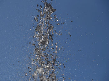 Close-up of water drops on leaf against blue sky