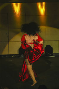 Portrait of woman with red umbrella standing at night