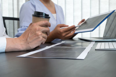 Midsection of businessman using laptop on table