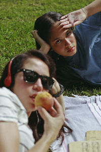 Woman eating fruit with friend on field