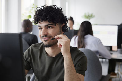 Man wearing headset using desktop pc in office