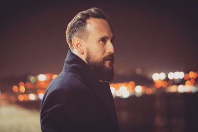 Portrait of man in city against sky at night