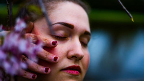 Woman with eyes closed touching face