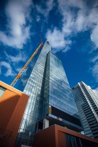 Low angle view of modern buildings against cloudy sky