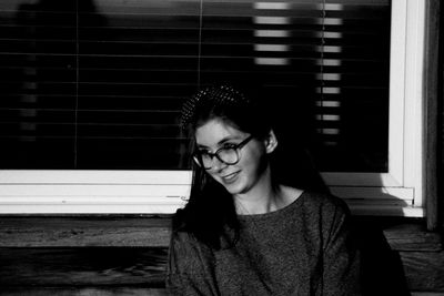 Smiling teenage girl wearing eyeglasses while looking away outside house at night