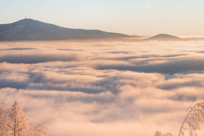 Rising sun in golden hour irradiates with its rays the impenetrable sea of clouds into orange color