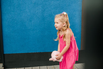 Portrait of young woman standing against wall