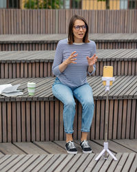 A young and confident woman blogger knits live broadcast from the phone or records content