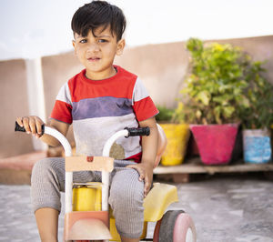 Portrait of boy sitting in tricycle outdoors