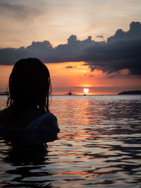 Woman looking at sea against sky during sunset